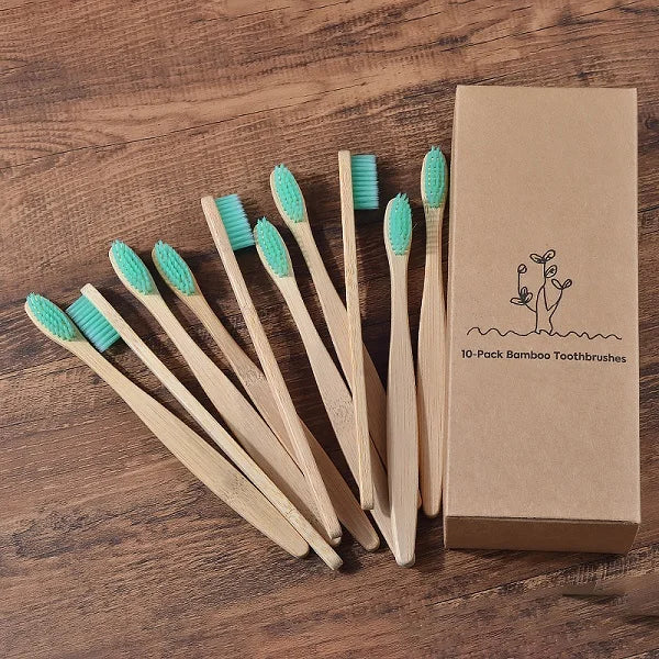 Une boîte contenant un pack de 10 brosses à dents en bambou vert clair, posées sur une surface en bois.