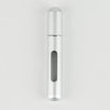 A sleek, cylindrical silver perfume bottle with a clear window for the liquid.