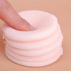 A hand is pressing down on a stack of soft pink velvet makeup puffs for concealer and powder.