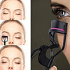 A close-up of a professional eyelash curler device and replacement pads being used on an eye.