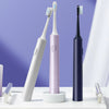 A white electric toothbrush and a purple electric toothbrush are displayed on a white surface against a purple background.