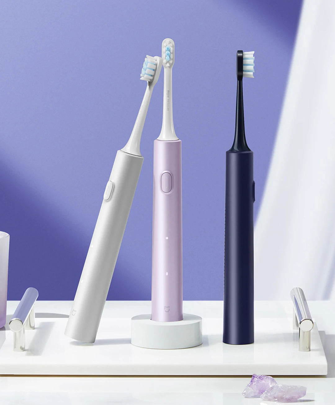 A white electric toothbrush and a purple electric toothbrush are displayed on a white surface against a purple background.