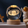 A glass crystal ball night light featuring a glowing solar system model on a wooden base.