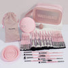 A pink professional makeup brush kit with various tools and a washbag is displayed on a white surface.
