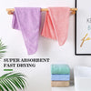 Two microfiber hair towels, one purple and one coral pink, are hanging on a wooden rack.