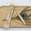 A bamboo toothbrush is shown lying on a wooden board next to a bundle of natural bristles.