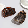 A pair of oval flat hair clips with a brown and black leopard print design.