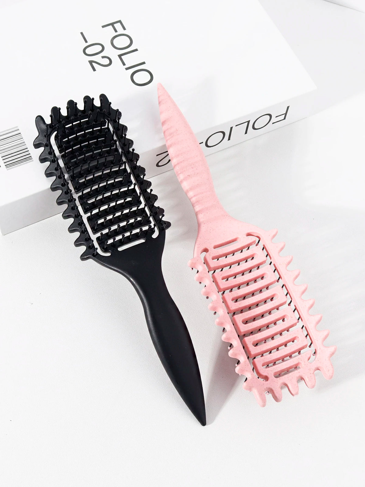 Peigne de coiffure professionnel en boucles noir et rose sur fond blanc.