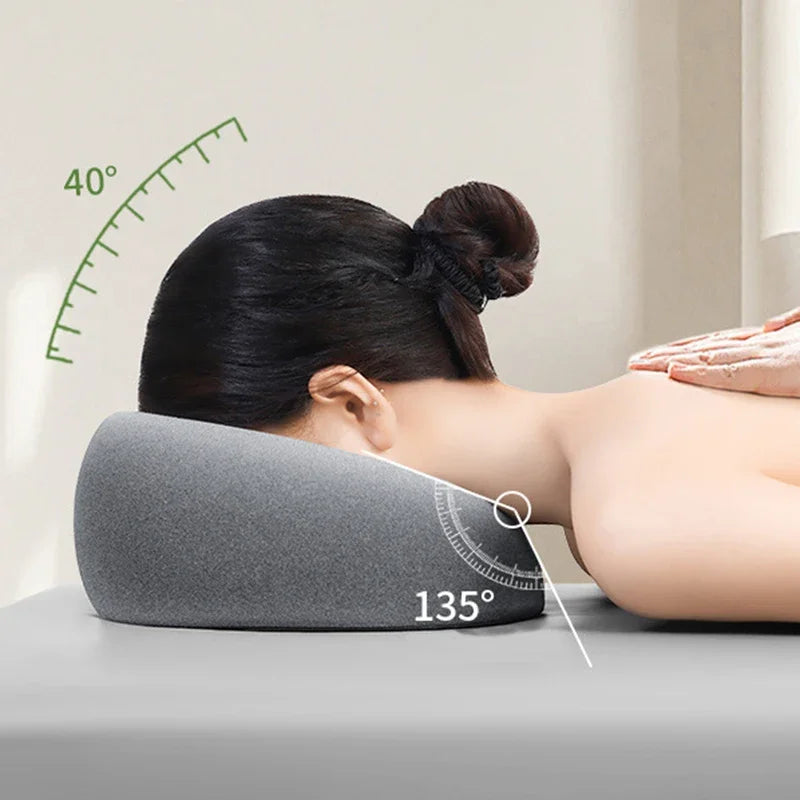 A person is lying down using a gray ergonomic memory foam pillow set at a 135-degree angle for relaxation.