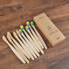 A box containing a set of ten natural bamboo toothbrushes is displayed on a wooden surface.