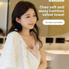 Une femme tient une serviette en velours de bambou blanc, montrant sa texture douce et cireuse.
