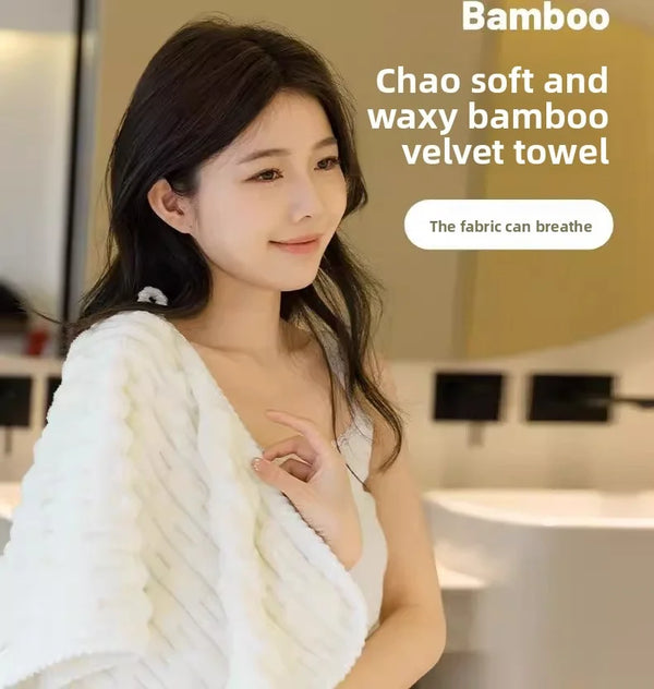 A woman is holding a white bamboo velvet towel, showcasing its soft and waxy texture.