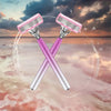 A pair of pink and silver safety razors are shown in an X shape, with water droplets circling them against a sunset sky.