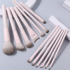A set of thirteen professional makeup brushes in a pale pink color arranged on a light gray surface.