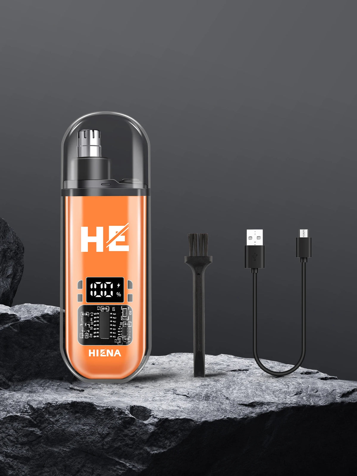An orange electric hair clipper set with a clear casing and black charging cable resting on a dark rock.