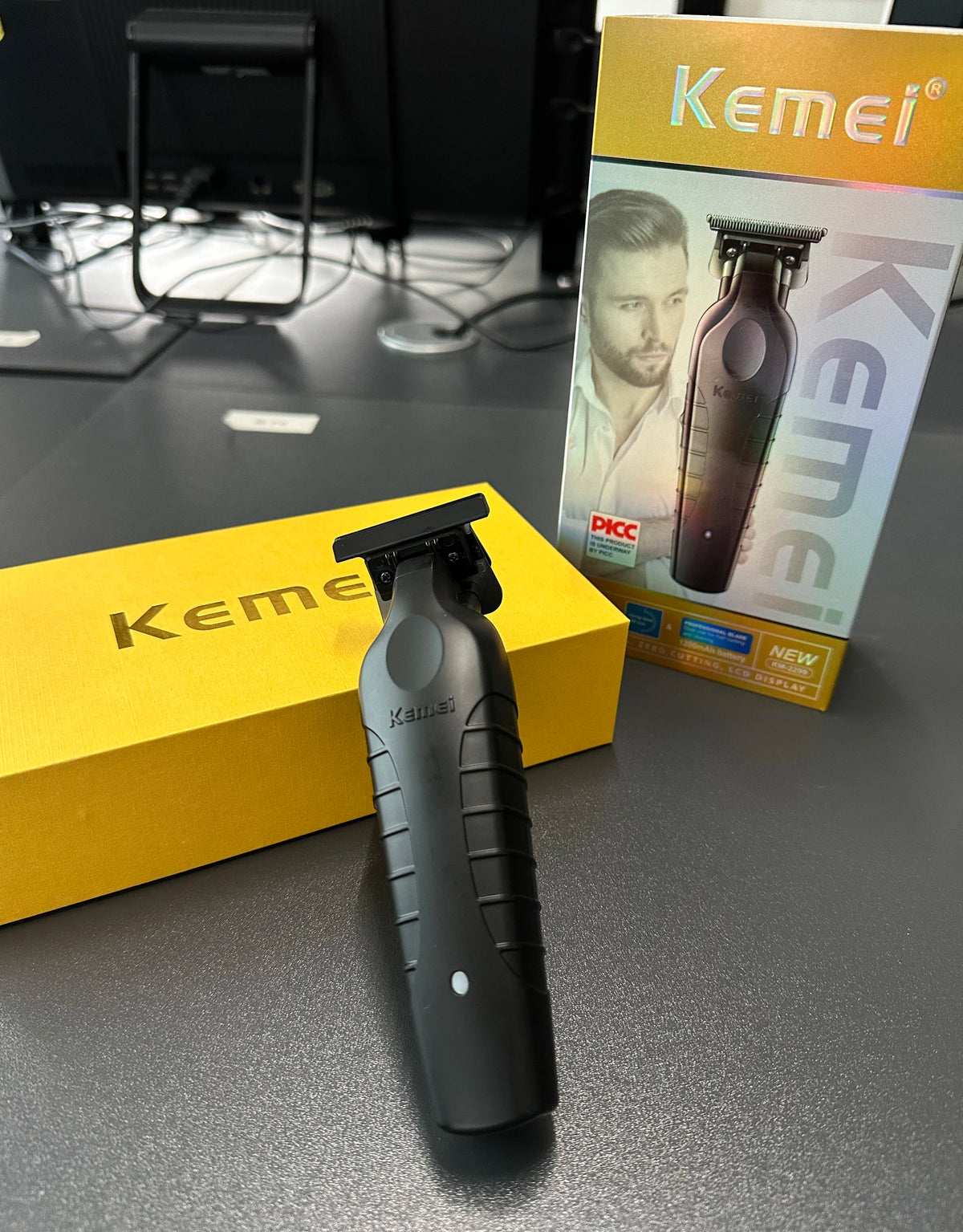 A black cordless electric hair clipper is displayed in front of its packaging box.
