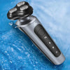A silver electric shaver and trimmer with a detachable head is shown submerged in blue water.