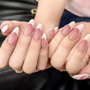 Close-up of hands displaying matte pink French press on artificial fingernails.