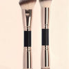 A pair of rose gold and black precision double-ended makeup foundation brushes standing upright.