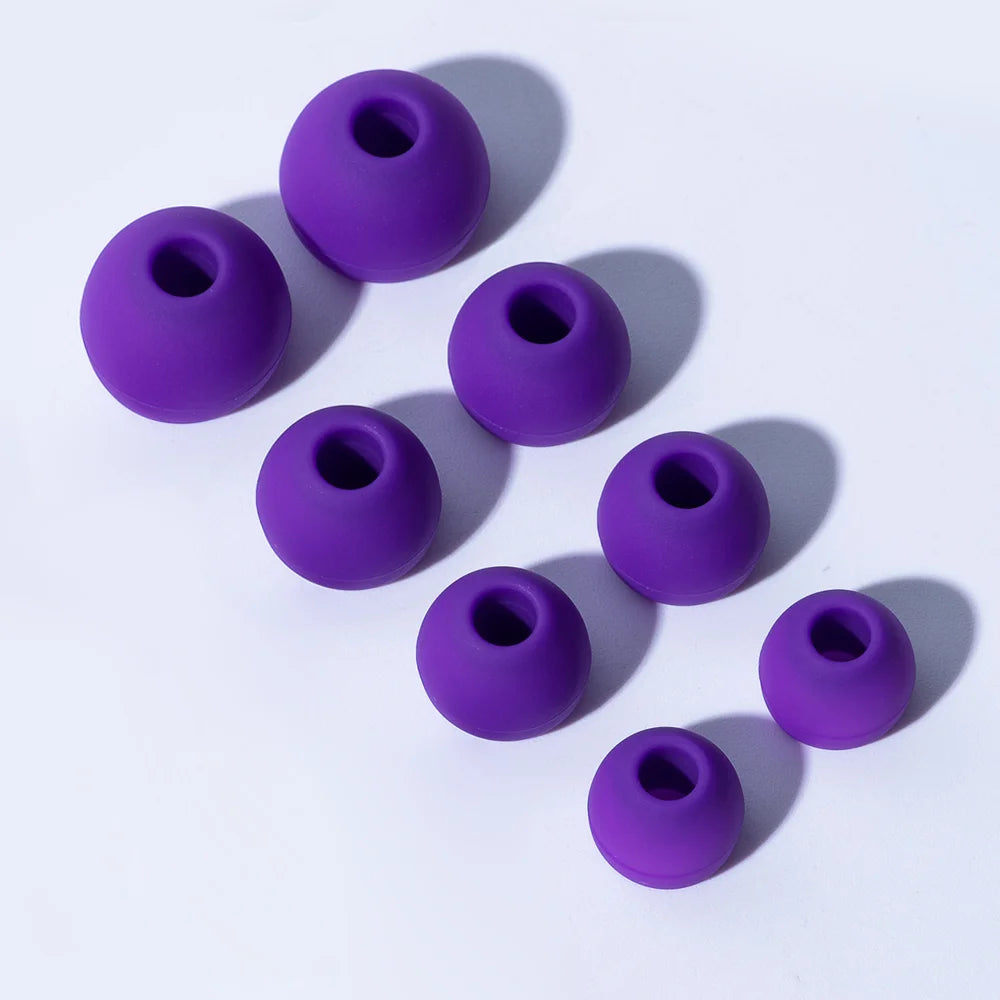 A collection of purple silicone earplugs arranged diagonally on a white background.