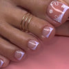 A close-up of a hand displaying press-on fake nails with short square French design and delicate floral accents.