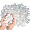 A hand holds a large quantity of white reusable compressed face towels packaged in clear plastic.