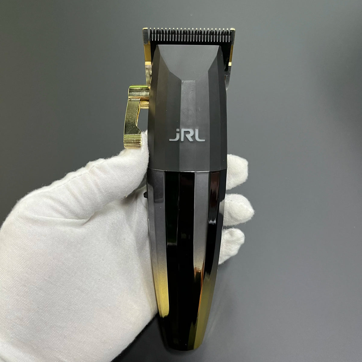 Eine Hand hält eine schwarze professionelle rotierende Haarschere mit goldfarbener Akzent und Metallaufsatz.