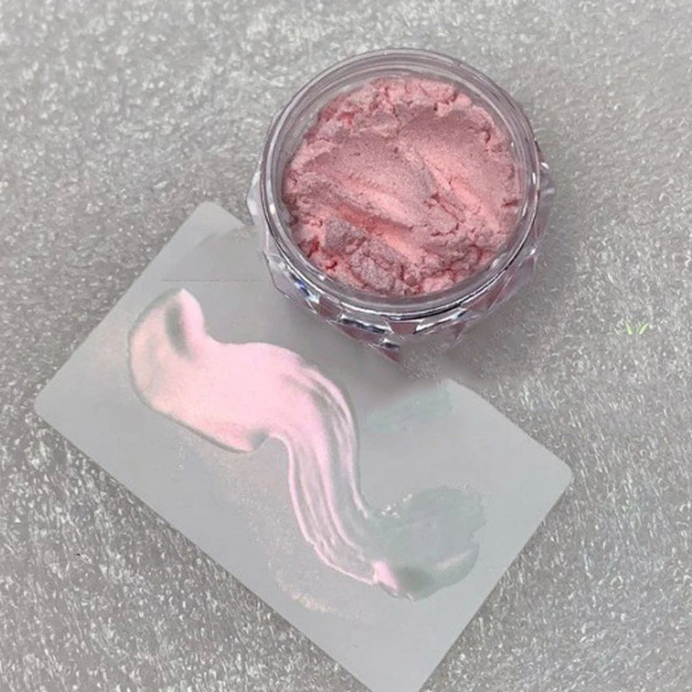 A jar of pink glitter powder with a pink cosmetic brush stroke displayed on a white card.