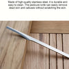 A silver pedicure knife is shown resting on a wooden surface.