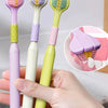 Une main tient un set de trois brosses à dents angulées avec des manches et poils violets, blancs et vert lime.