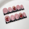 Un set de uñas postizas nude rosa con acabado brillante y un pequeño diseño de manzana roja.