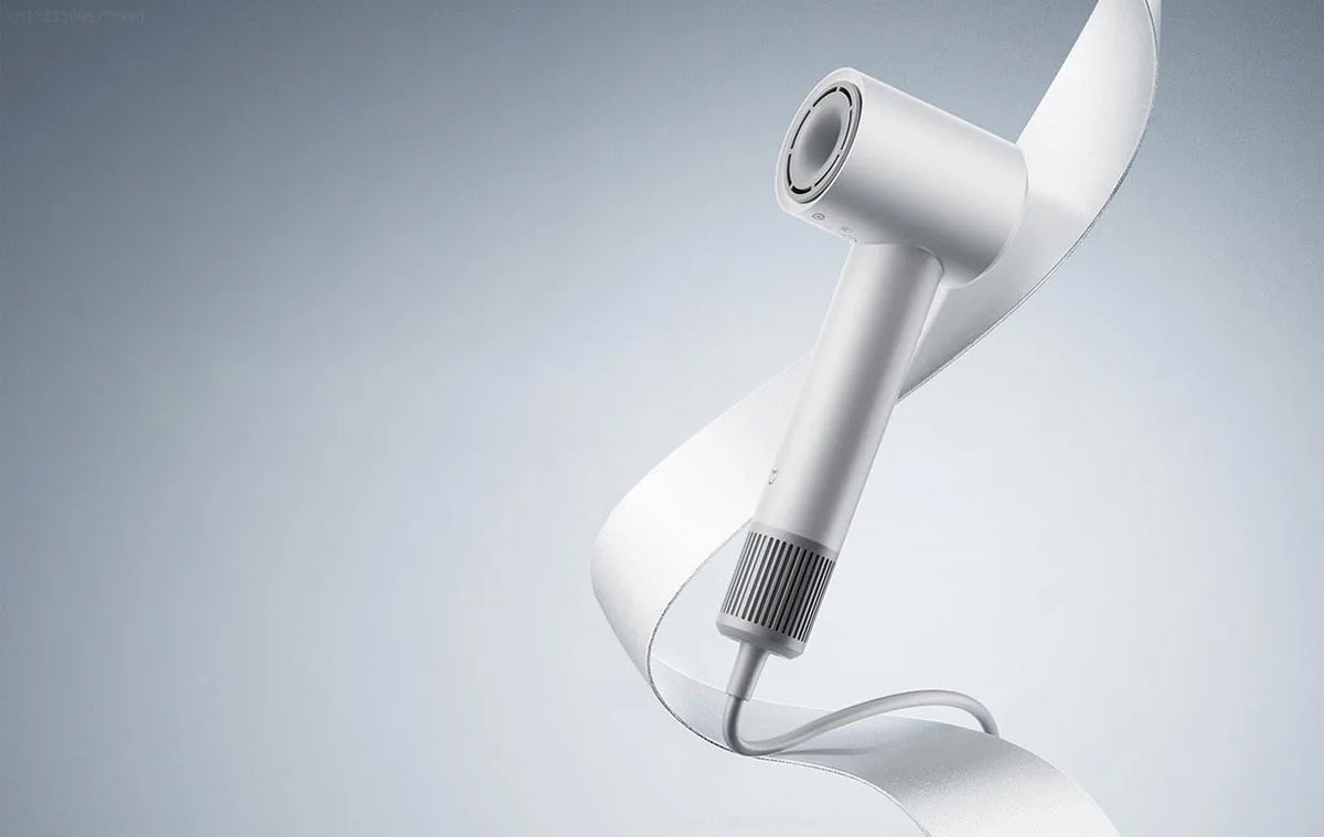 A white professional high-speed hair dryer is shown in a close-up, curved view against a light gray background.