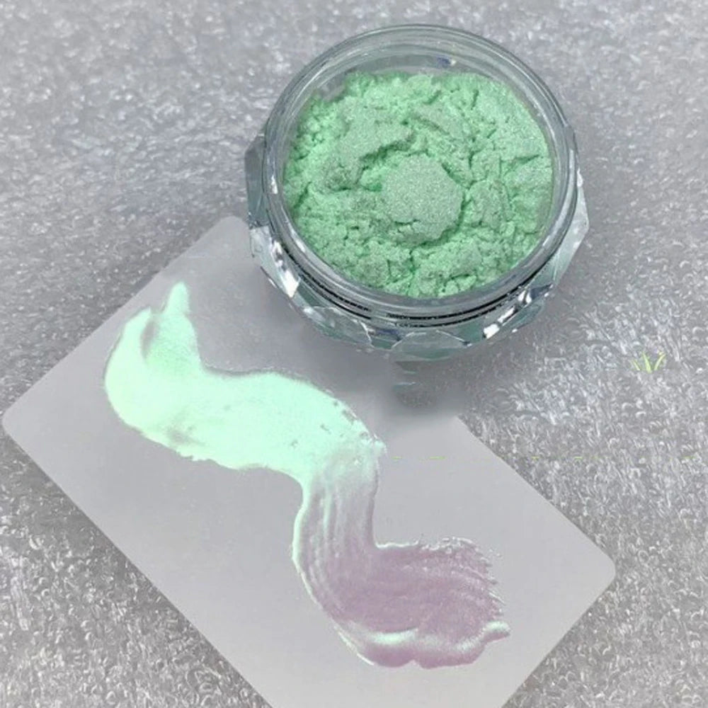 A jar of mint green glitter powder next to a swatch of light purple nail art.
