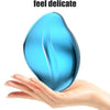 A hand holds a smooth, teardrop-shaped blue glass tool designed to fit the palm curve for delicate use.
