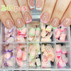 Une boîte de 240 ongles pressions avec différentes couleurs rose pastel, blanc et vert pour un manucure acrylique.