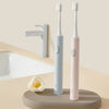 A pair of pink and light blue sonic electric toothbrushes are displayed next to a white sink and faucet.