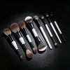 A collection of black and white dual-ended makeup brushes for foundation and contour displayed on a dark surface.