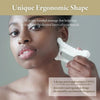 A woman holds a white resin facial gua sha massage tool near her face.
