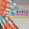 A hand displays various multi-color 3D hibiscus flower nail decals on fingernails.