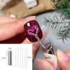 A hand holds a silver nail magnet wand set with a purple cat eye design and a measuring scale.