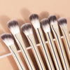 A set of thirteen professional makeup brushes with light wood handles and gray bristles displayed on a neutral background.