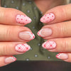 Close-up of hands displaying reusable pink and red striped press-on nails on fingers