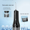A black portable electric dental floss and oral irrigator with a removable water tank shown in use.