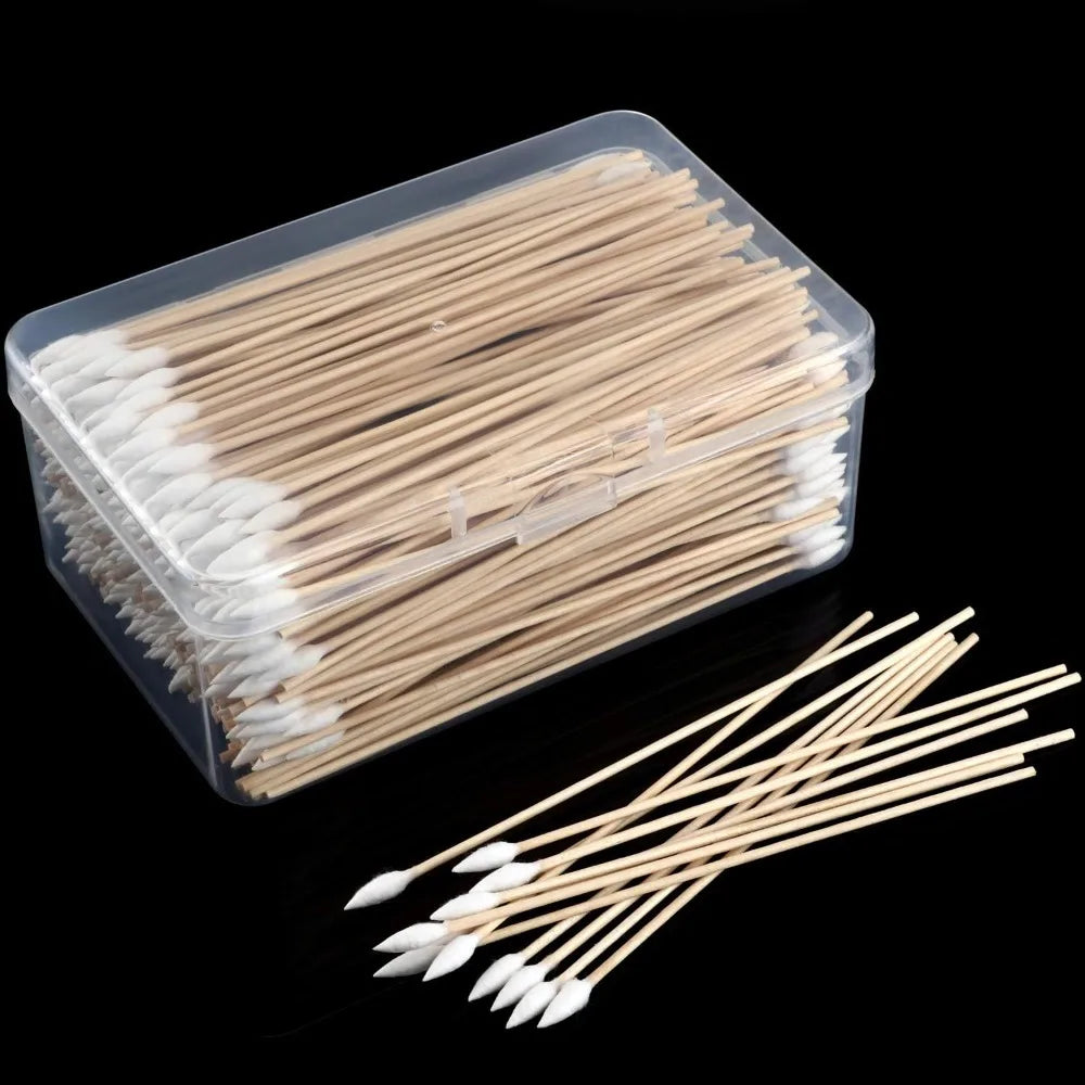 A clear plastic container filled with numerous wooden cotton swabs and cotton tips.