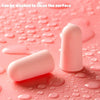 Pink foam earplugs resting on a pink surface with water droplets, indicating they can be washed.