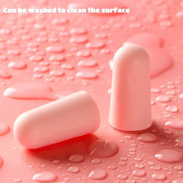 Pink foam earplugs resting on a pink surface with water droplets, indicating they can be washed.