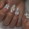 A hand displays 24 pink heart pearl press-on fake nails with glitter accents on fingers.