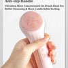 A hand holds a pink sonic facial cleansing brush with a shock-absorbing ergonomic and anti-slip handle.