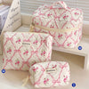 A quilted pink and white floral cotton makeup bag with a zipper closure shown in various sizes.