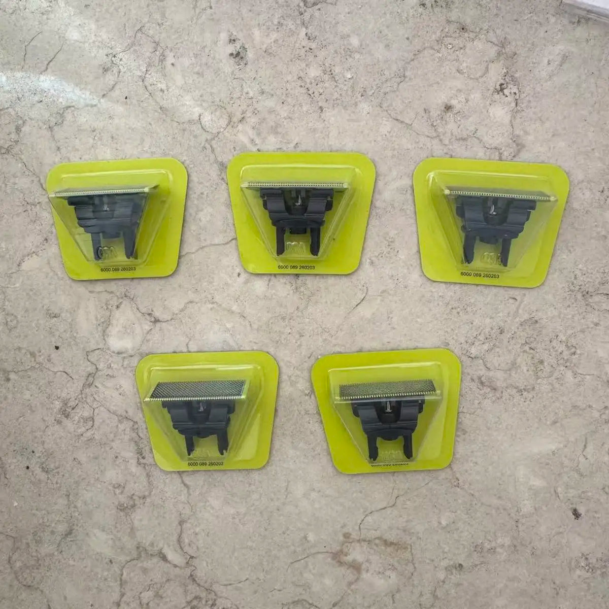 Four yellow plastic holders for a precision electric beard trimmer with black attachments.